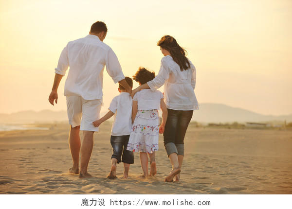 快乐的年轻家庭在日落的海滩上玩耍幸福一家人